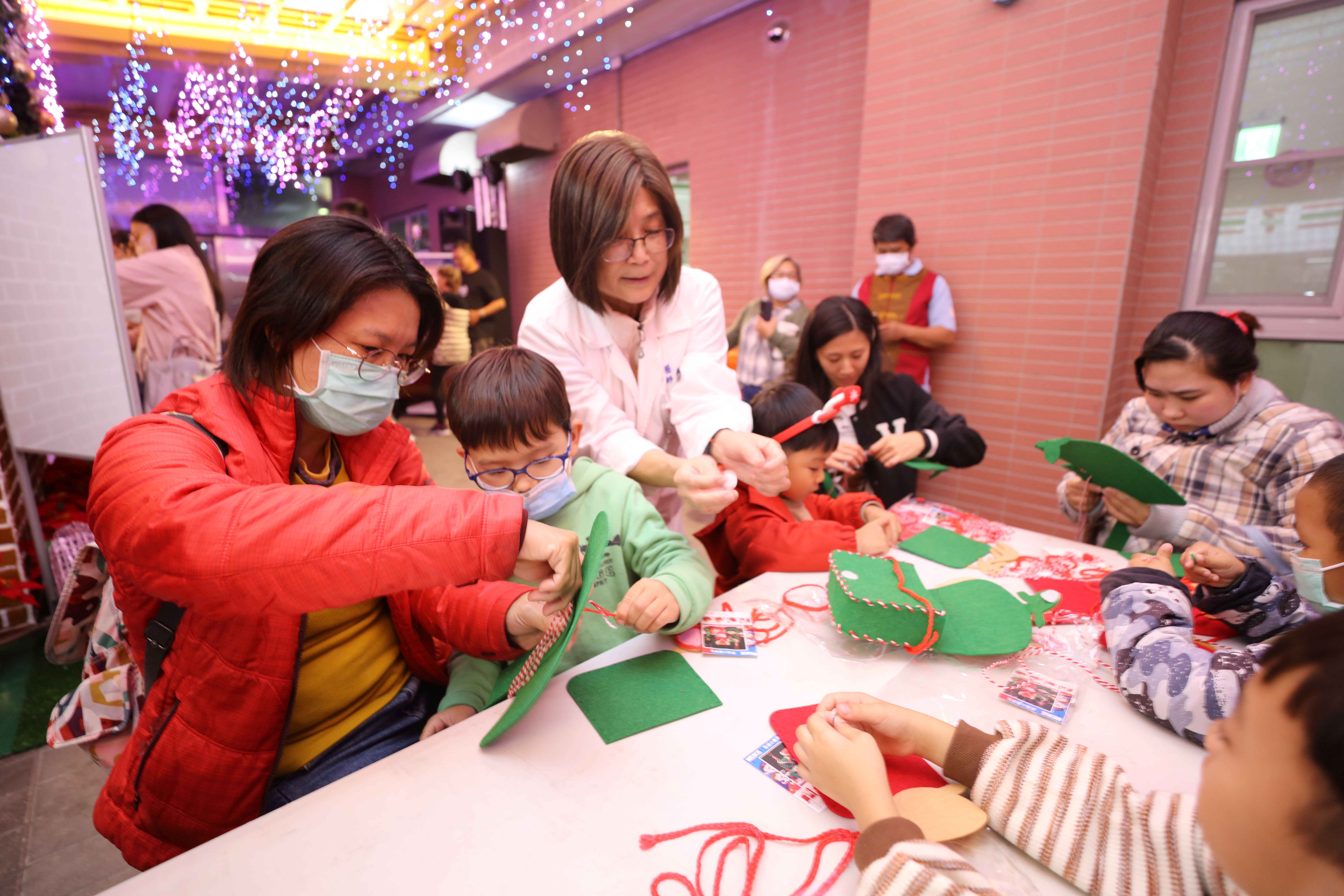 點燈儀式後，親子手作聖誕小包包，創造獨一無二親子回憶。顏簡院長(左三)幫忙孩子穿線。 (恆基提供)